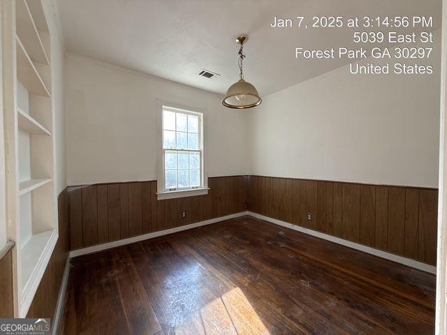 spare room with dark hardwood / wood-style flooring and wood walls