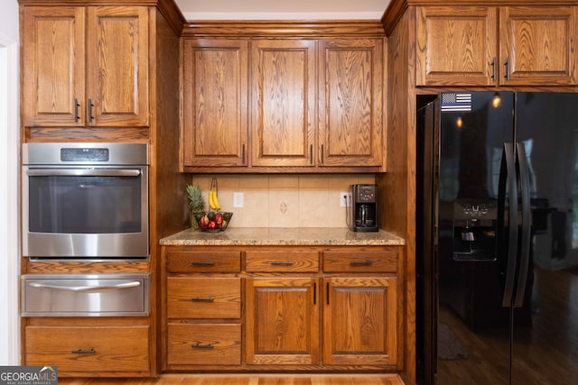 kitchen with decorative backsplash, oven, black refrigerator with ice dispenser, and light stone countertops