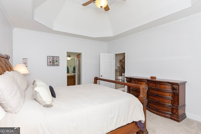 bedroom featuring ensuite bath, ceiling fan, a tray ceiling, ornamental molding, and light colored carpet