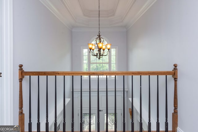 staircase with ornamental molding, a tray ceiling, and a notable chandelier