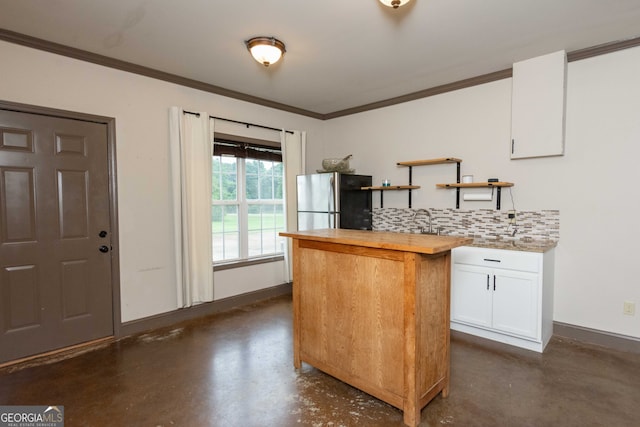 kitchen with sink, white cabinets, stainless steel fridge, backsplash, and ornamental molding