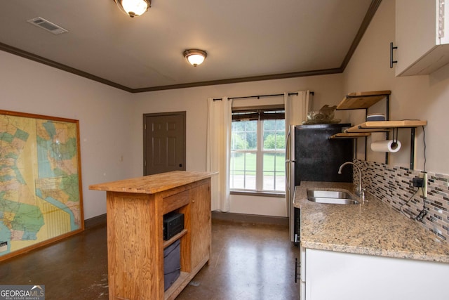 kitchen with sink, white cabinetry, light stone counters, ornamental molding, and decorative backsplash