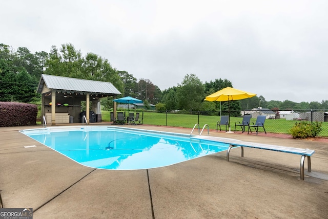 view of swimming pool with an outbuilding, a lawn, a diving board, and a patio area