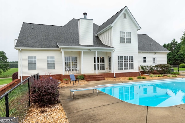 rear view of house with a fenced in pool and a patio area