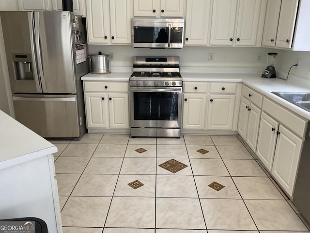 kitchen with white cabinetry, appliances with stainless steel finishes, sink, and light tile patterned floors