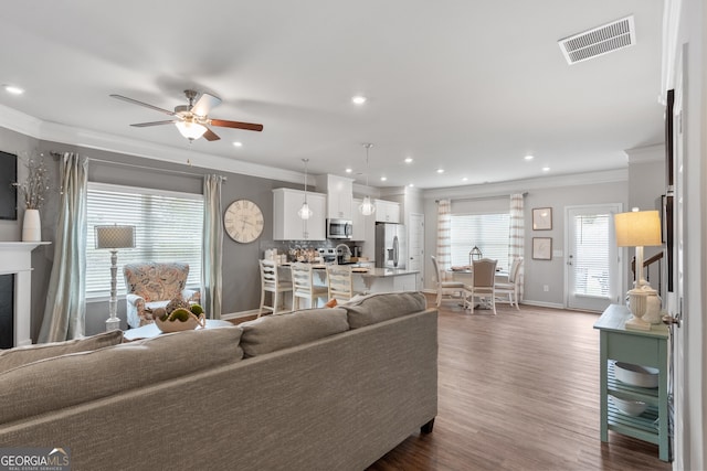 living room with crown molding, dark wood-type flooring, and ceiling fan