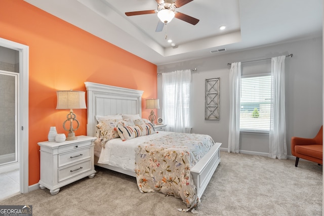 carpeted bedroom featuring a raised ceiling and ceiling fan