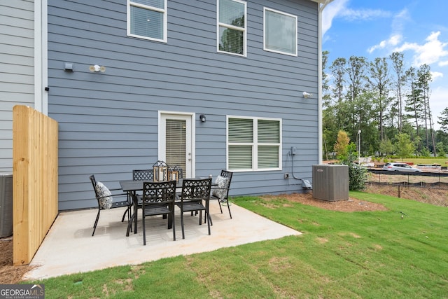 back of property with a lawn, central air condition unit, and a patio area