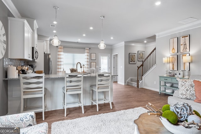 kitchen featuring decorative light fixtures, white cabinetry, a kitchen breakfast bar, stainless steel appliances, and light stone countertops