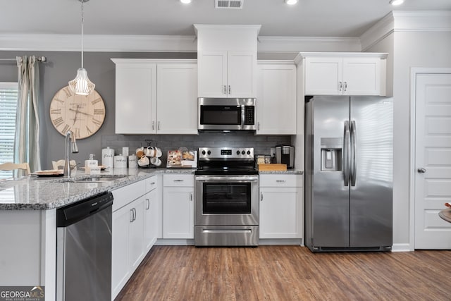 kitchen featuring sink, white cabinetry, hanging light fixtures, stainless steel appliances, and ornamental molding