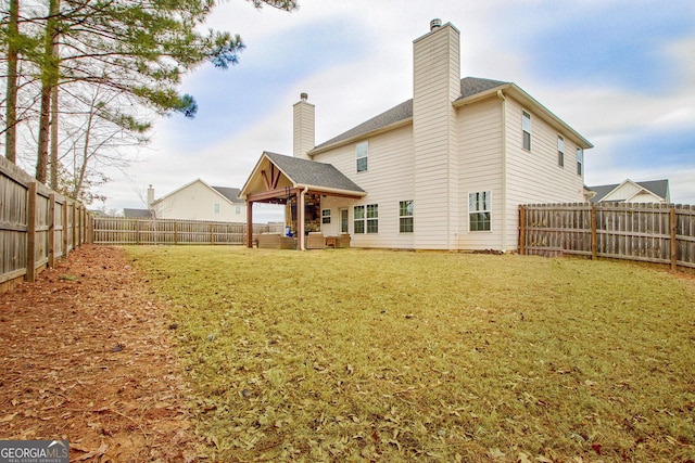 back of property featuring a gazebo, a fenced backyard, a chimney, and a yard