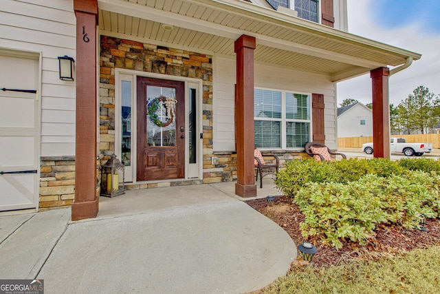 entrance to property featuring stone siding and a porch