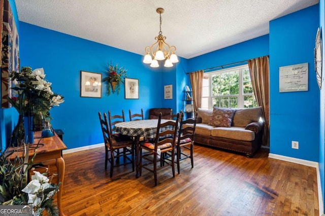 dining area with dark hardwood / wood-style flooring, a textured ceiling, and an inviting chandelier