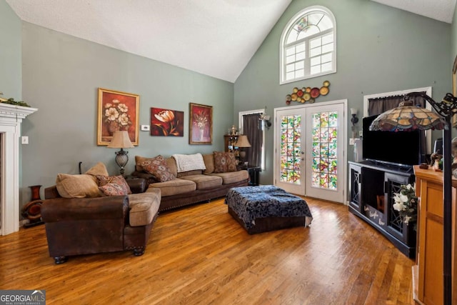 living room with hardwood / wood-style flooring, high vaulted ceiling, french doors, and a healthy amount of sunlight