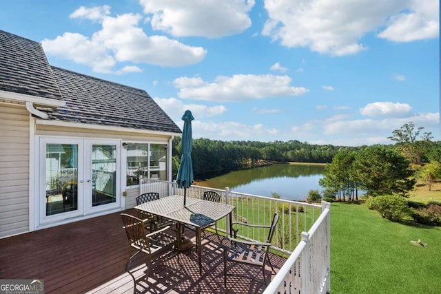 wooden deck with a water view, a lawn, and french doors