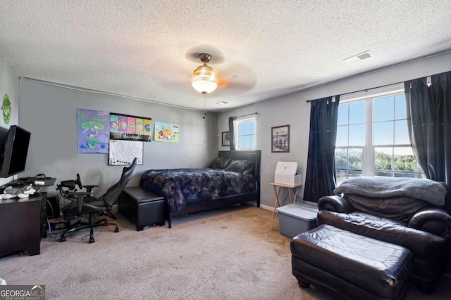 bedroom with ceiling fan, carpet flooring, and a textured ceiling