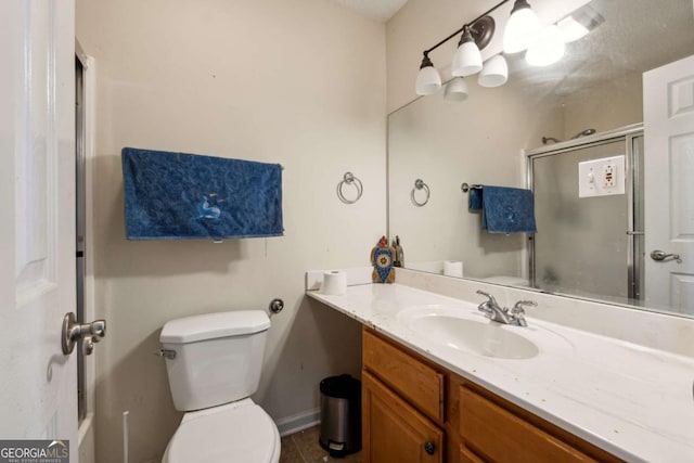 bathroom with vanity, a shower with door, and toilet