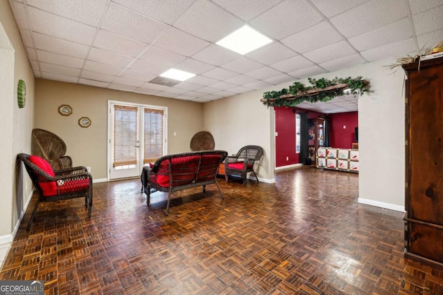 living room with a paneled ceiling and dark parquet floors