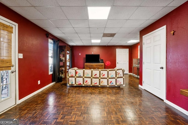 living room with a paneled ceiling and dark parquet flooring