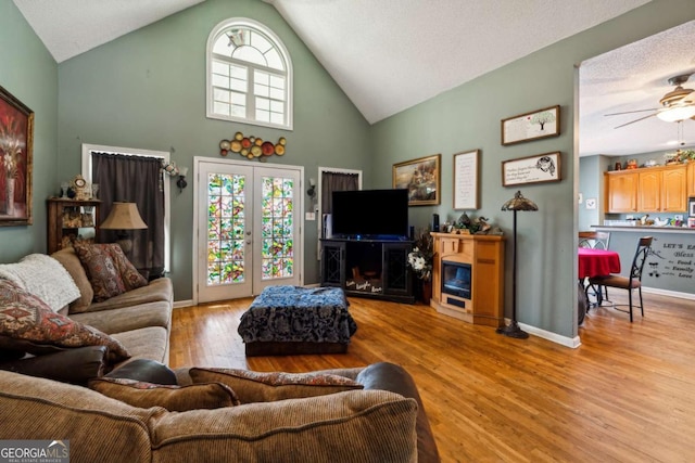 living room featuring light hardwood / wood-style flooring, high vaulted ceiling, and ceiling fan