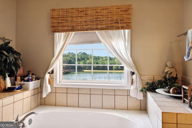 bathroom with tiled bath and a water view