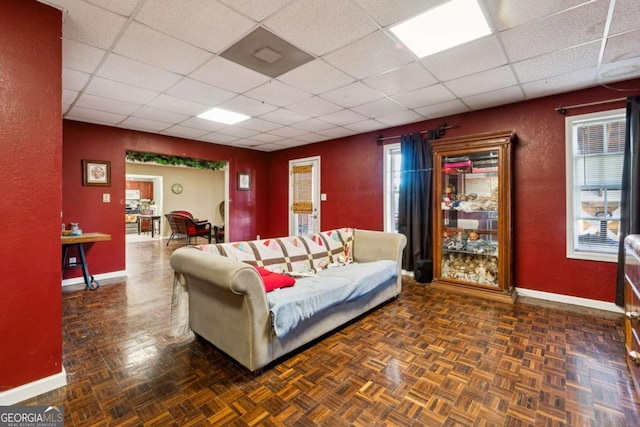 living room featuring a drop ceiling and dark parquet floors