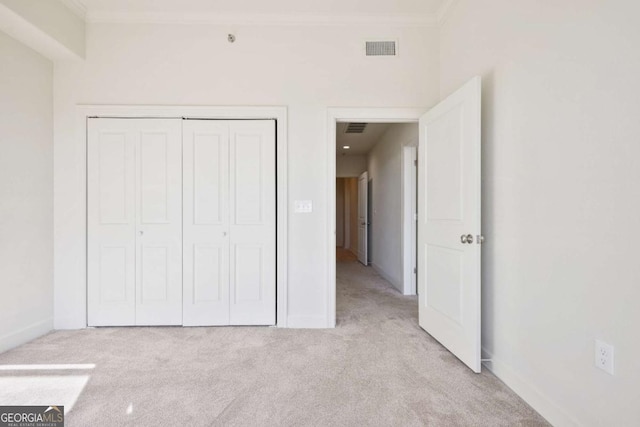 unfurnished bedroom featuring light carpet, crown molding, and a closet