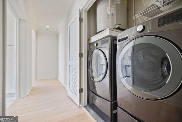 laundry area with crown molding, separate washer and dryer, and light hardwood / wood-style floors