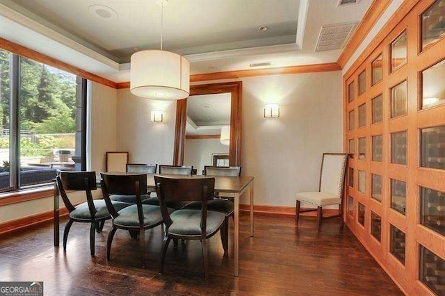 dining area with ornamental molding, dark hardwood / wood-style flooring, and a raised ceiling