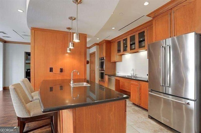 kitchen featuring sink, decorative light fixtures, stainless steel appliances, and a kitchen bar