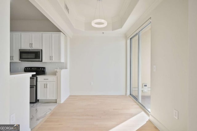 corridor featuring crown molding, a raised ceiling, and light hardwood / wood-style flooring