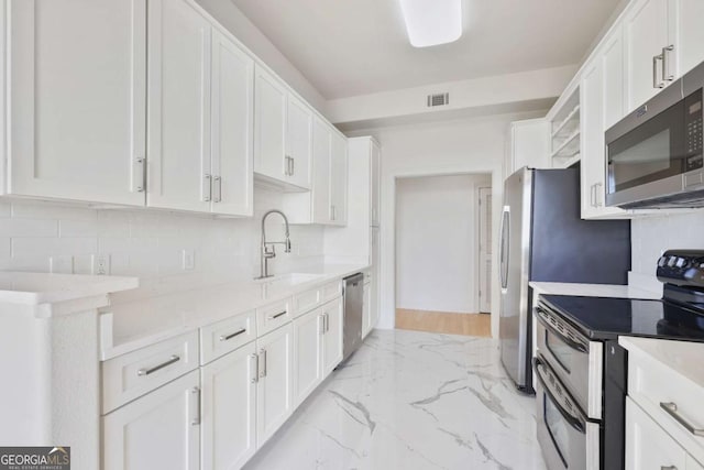 kitchen featuring stainless steel appliances, white cabinets, and backsplash