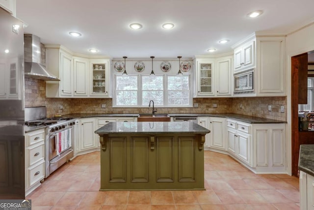 kitchen with wall chimney exhaust hood, sink, a center island, dark stone counters, and stainless steel appliances