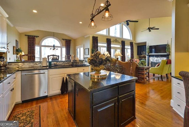 kitchen with dishwasher, white cabinets, a kitchen island, decorative light fixtures, and vaulted ceiling