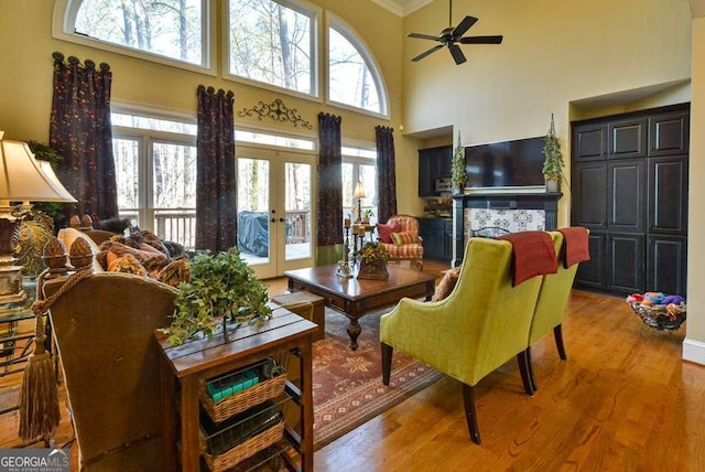 living room with french doors, ceiling fan, light hardwood / wood-style floors, and a high ceiling