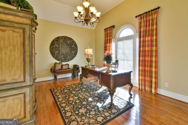 office area featuring an inviting chandelier, vaulted ceiling, and light hardwood / wood-style floors