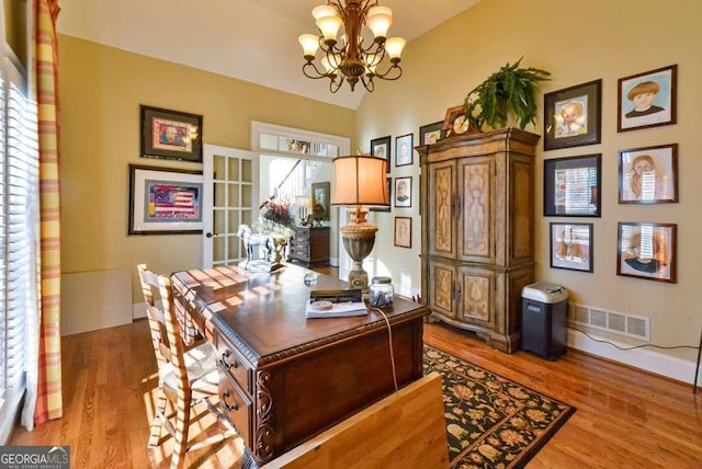 office with an inviting chandelier, vaulted ceiling, and light wood-type flooring