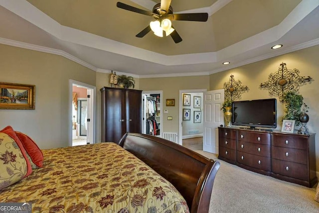 carpeted bedroom featuring ceiling fan, connected bathroom, ornamental molding, a spacious closet, and a raised ceiling