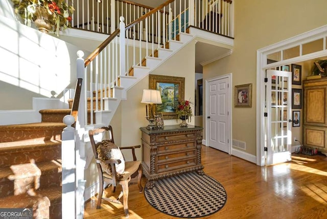 stairway with a towering ceiling and wood-type flooring