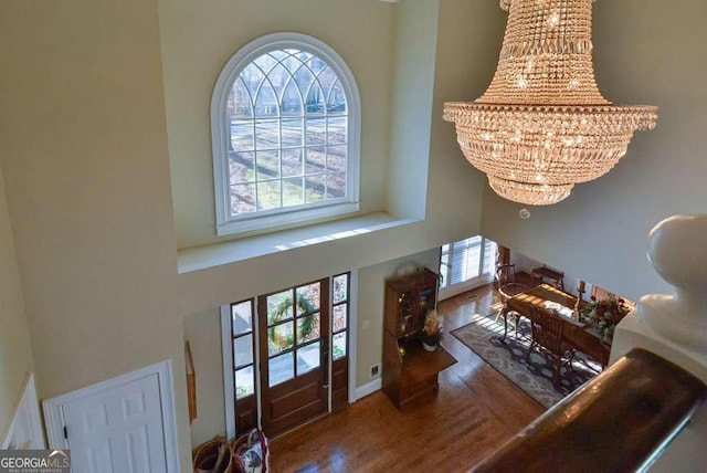 interior space with a high ceiling, a healthy amount of sunlight, hardwood / wood-style floors, and a notable chandelier