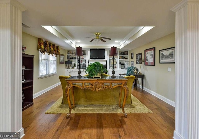 dining area featuring ceiling fan, wood-type flooring, a raised ceiling, and built in features