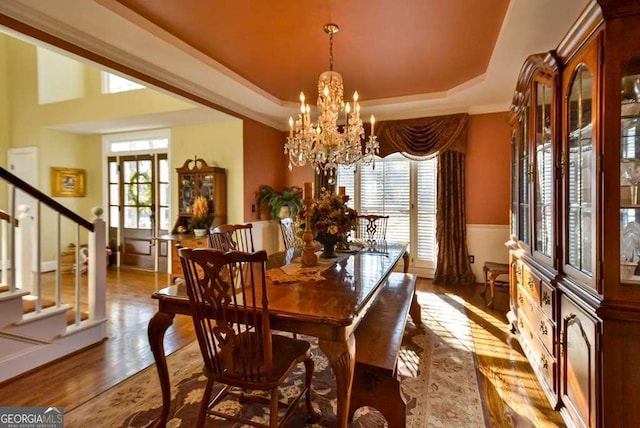 dining room featuring plenty of natural light, a raised ceiling, light hardwood / wood-style flooring, and a notable chandelier