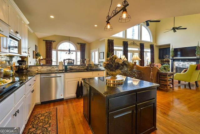 kitchen featuring lofted ceiling, white cabinetry, stainless steel appliances, dark hardwood / wood-style floors, and a center island