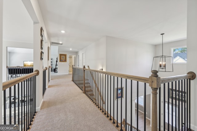 hallway featuring light carpet and a notable chandelier