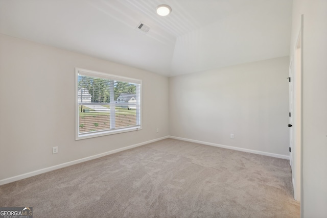 empty room featuring vaulted ceiling and light colored carpet