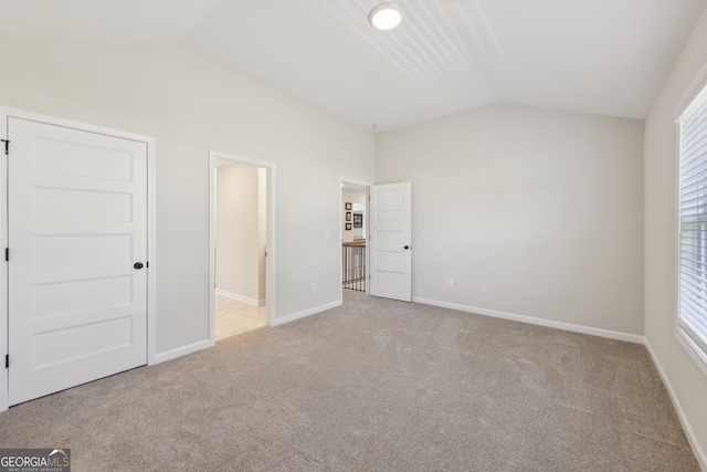 unfurnished bedroom featuring lofted ceiling and light carpet