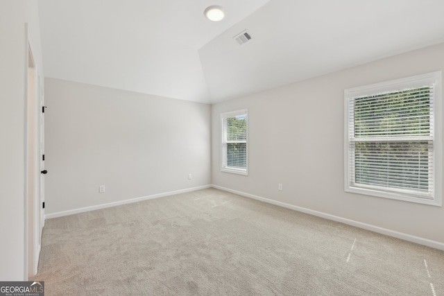 carpeted empty room featuring lofted ceiling