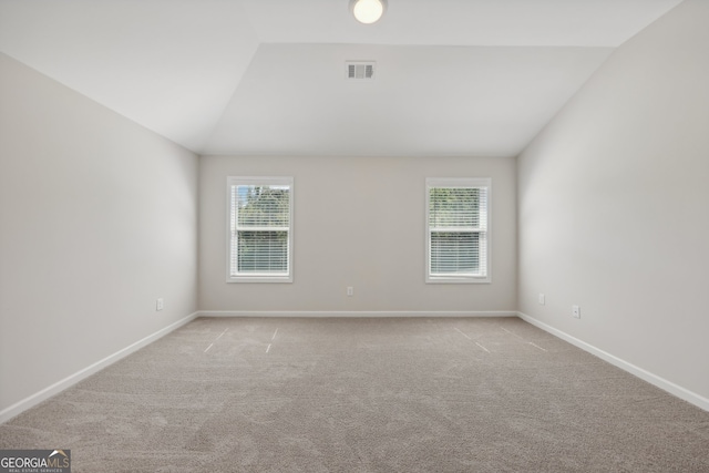 carpeted empty room featuring vaulted ceiling