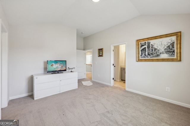 carpeted bedroom with ensuite bathroom and vaulted ceiling