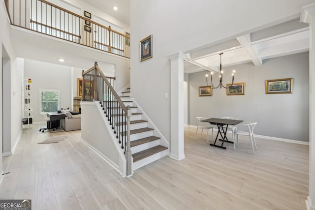 stairway featuring coffered ceiling, a chandelier, hardwood / wood-style flooring, beam ceiling, and a high ceiling